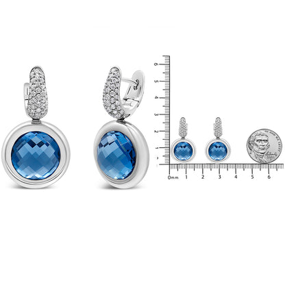 Front and side view of white metal earrings with round blue gemstones in bezel setting, topped with pavé-set white gemstones, shown next to a ruler and coin for size reference.