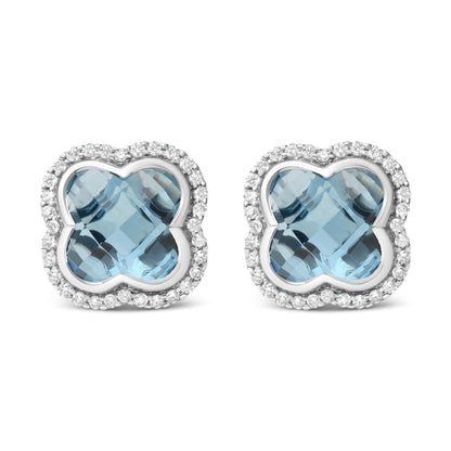 Front view of white metal earrings with a blue gemstone center in a unique shape, surrounded by a border of round white gemstones in prong settings.
