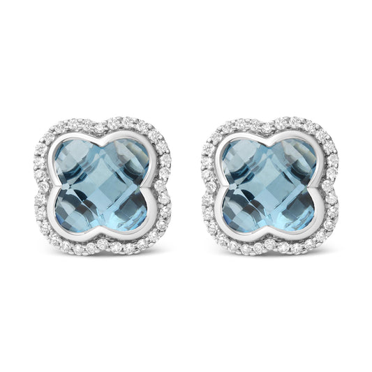 Front view of white metal earrings with a blue gemstone center in a unique shape, surrounded by a border of round white gemstones in prong settings.