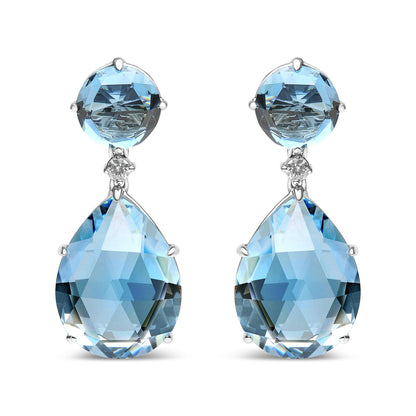 Front view of white metal earrings with a round blue gemstone at the top, a small white gemstone below it, and a large pear-shaped blue gemstone hanging at the bottom.