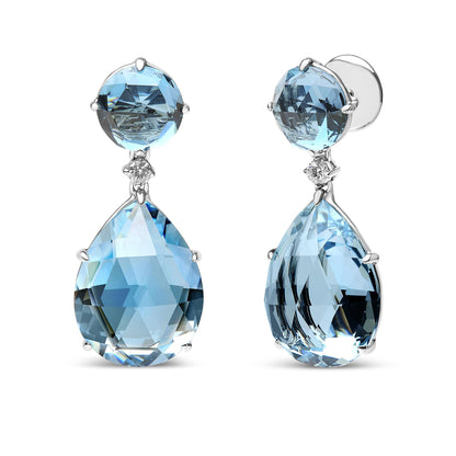 Close-up front and side view of white metal drop earrings with round blue gemstones at the top, small white gemstones below them, and large pear-shaped blue gemstones hanging below.