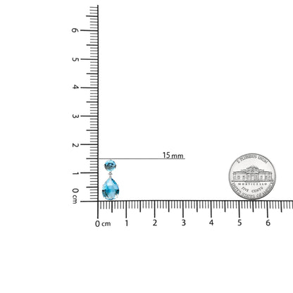 Single white metal earring with round white gemstones at the top and pear-shaped and round blue gemstones hanging below, shown on a ruler for size reference, front angled view.