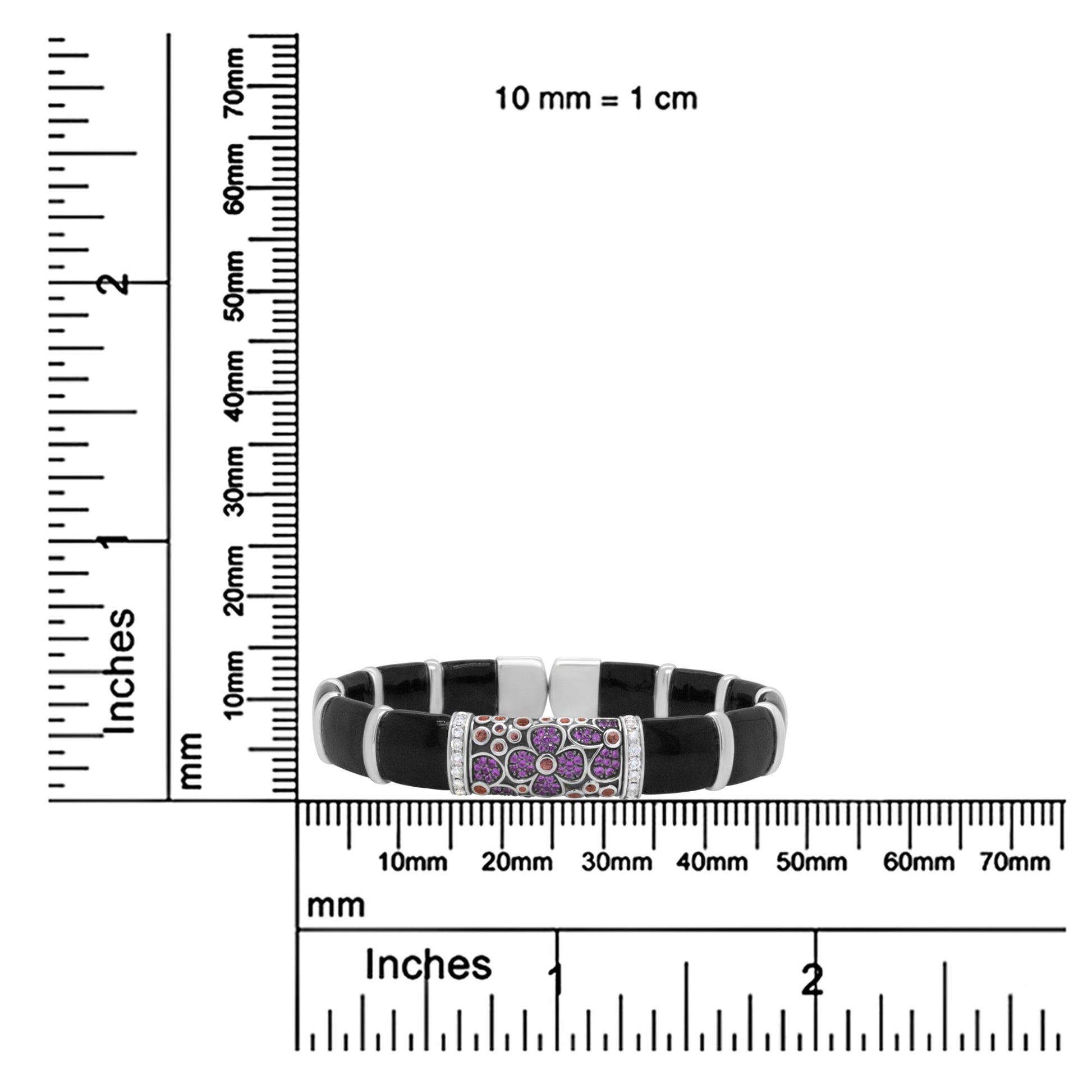 White metal bracelet with black segments and a central floral design featuring round pink and orange gemstones and white gemstones, bezel and prong settings, displayed on a ruler for size reference, front view.