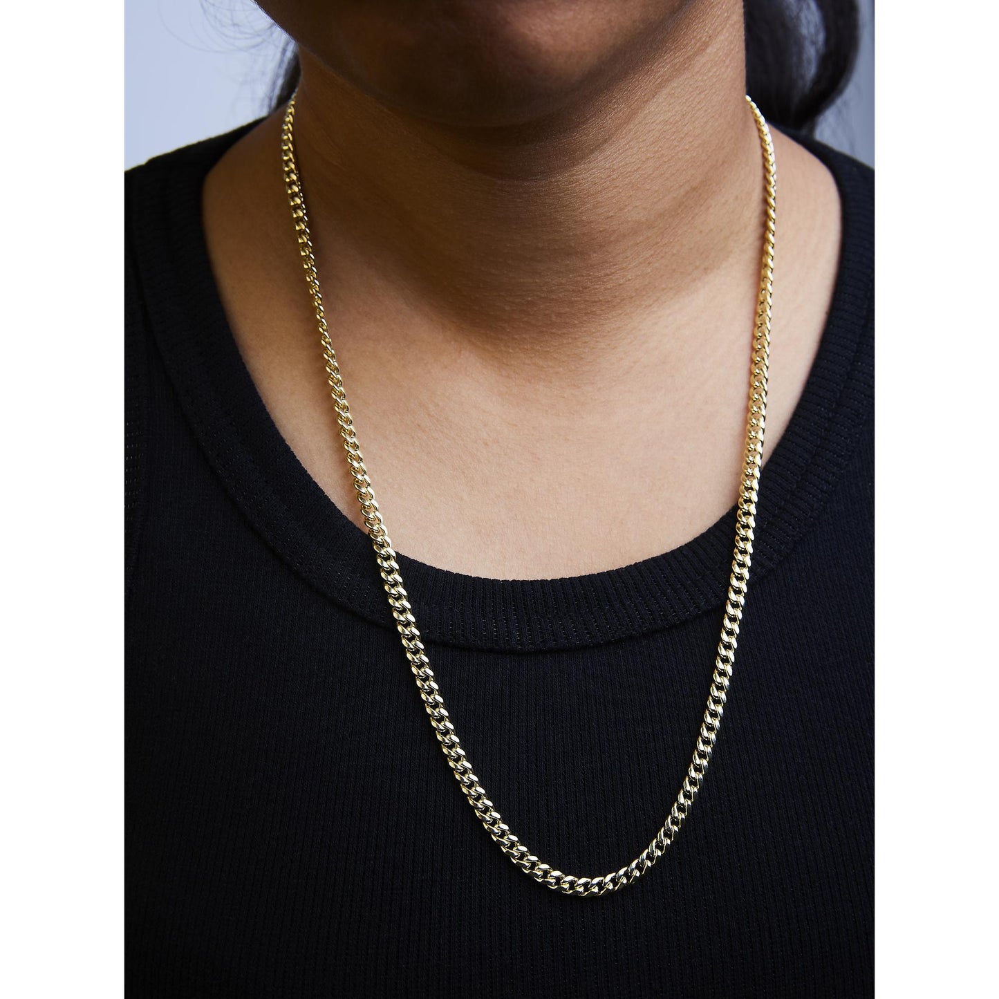 Yellow metal chain necklace shown worn on a model, front view focusing on the neckline.
