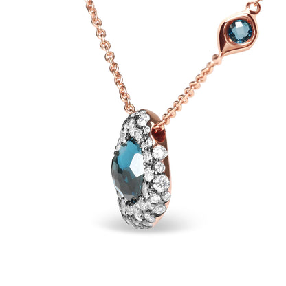 Close-up front angled view of a rose metal necklace with a pendant featuring a central blue gemstone surrounded by multiple prong-set white gemstones, and a small bezel-set white gemstone and a small bezel-set blue gemstone on the chain.
