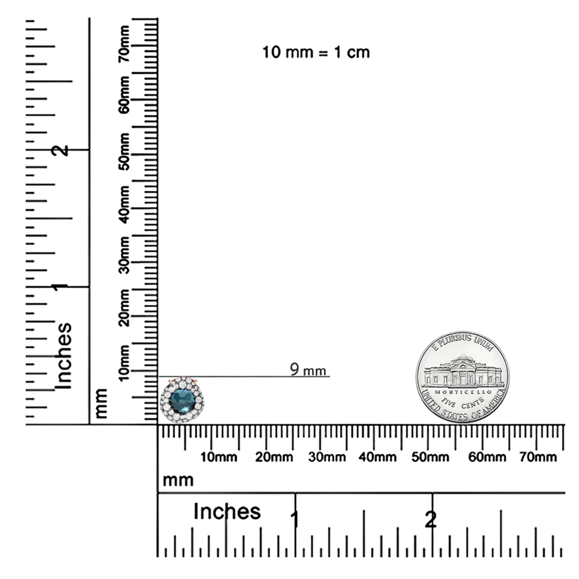 Rose metal necklace pendant with a round blue gemstone in bezel setting surrounded by small round white gemstones in prong setting, shown on a ruler for size reference.