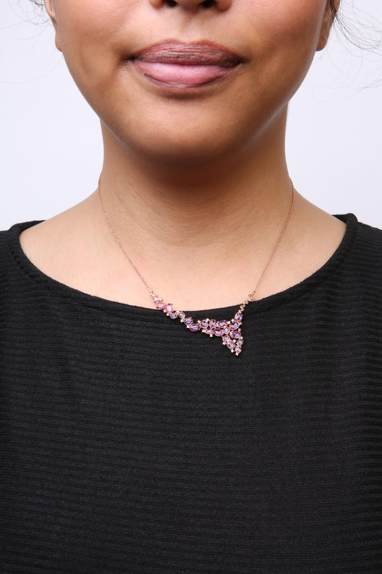 Close-up front view of a rose metal necklace on a model, featuring pink oval-shaped gemstones and brown round-shaped gemstones in prong settings, arranged in a V-shaped cluster.