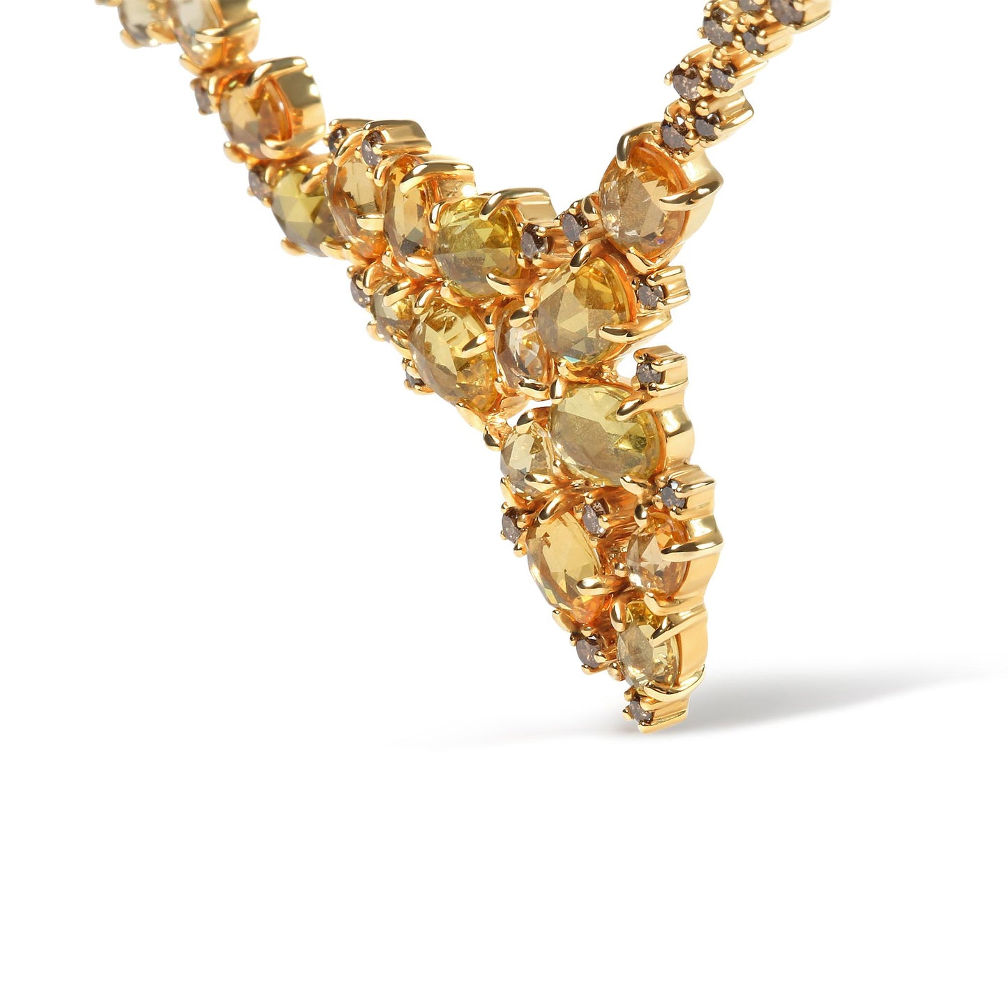 Close-up angled shot of a yellow metal necklace with oval yellow gemstones and round brown gemstones in prong settings.