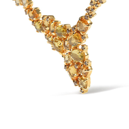 Close-up angled shot of a yellow metal necklace with oval yellow gemstones and round brown gemstones in prong settings.