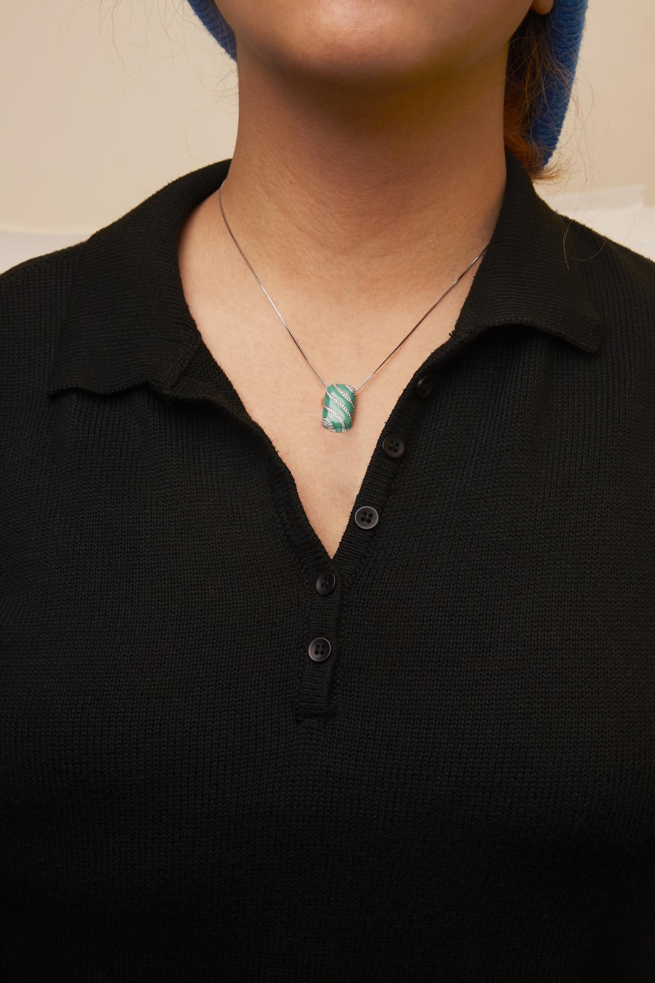 Front view of a white metal necklace with a green pendant featuring diagonal stripes of round white gemstones, worn on a model.