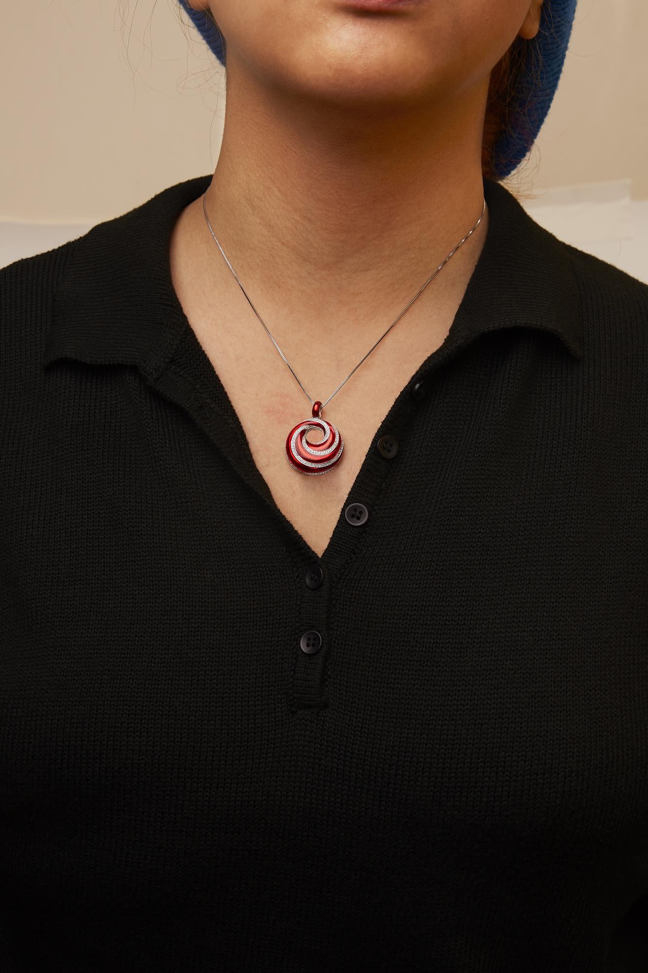 White metal necklace with a round red and white gemstone pendant in a spiral design, worn on a model, front-facing angle.