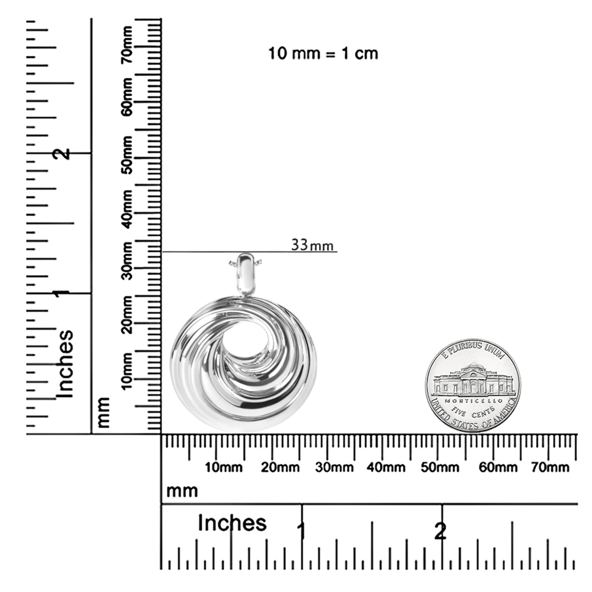 White metal circular swirl design pendant necklace shown from the front, placed on rulers and a coin for size reference.