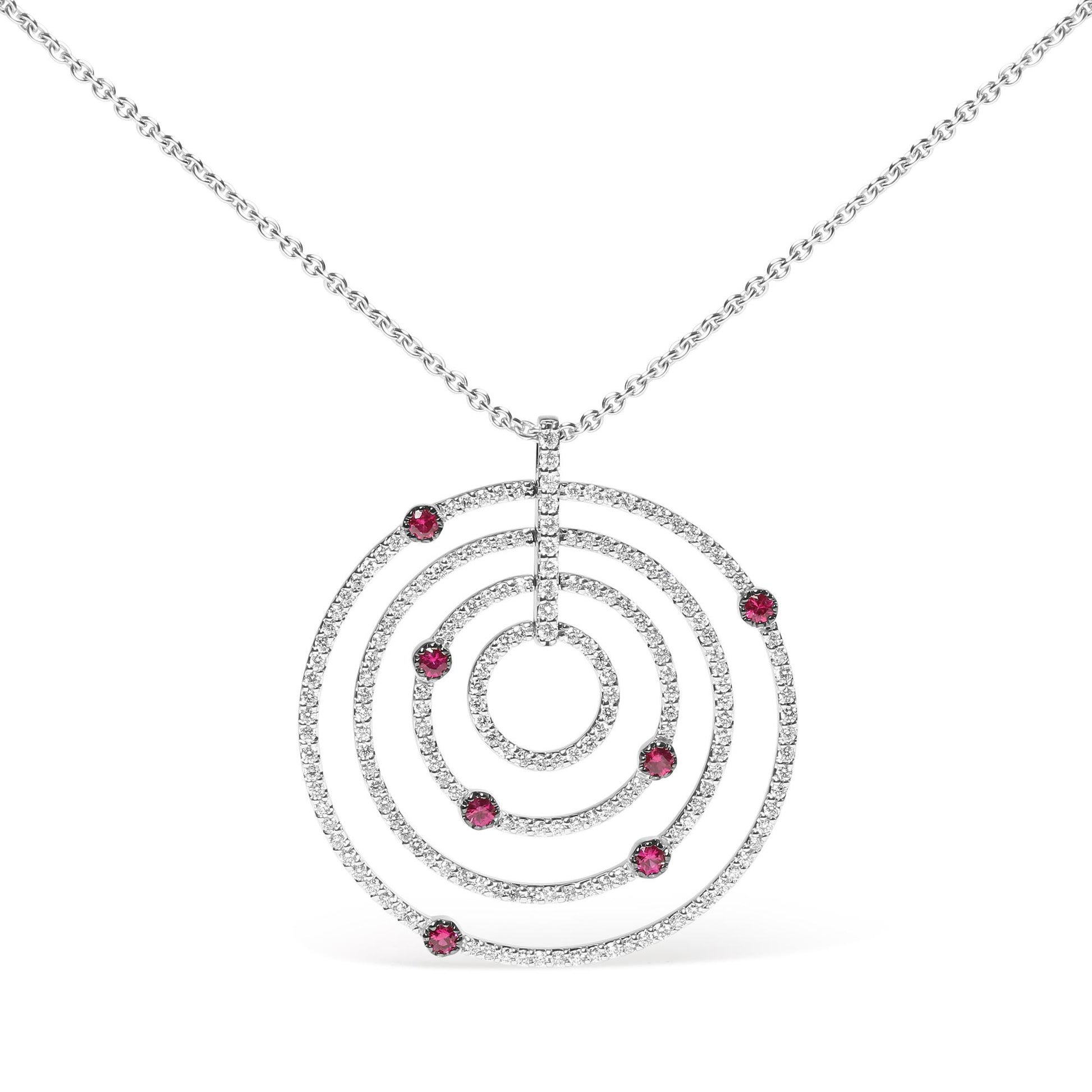 Front view of a white metal necklace with a circular pendant featuring concentric rings encrusted with white gemstones and accented with red gemstones on each ring.