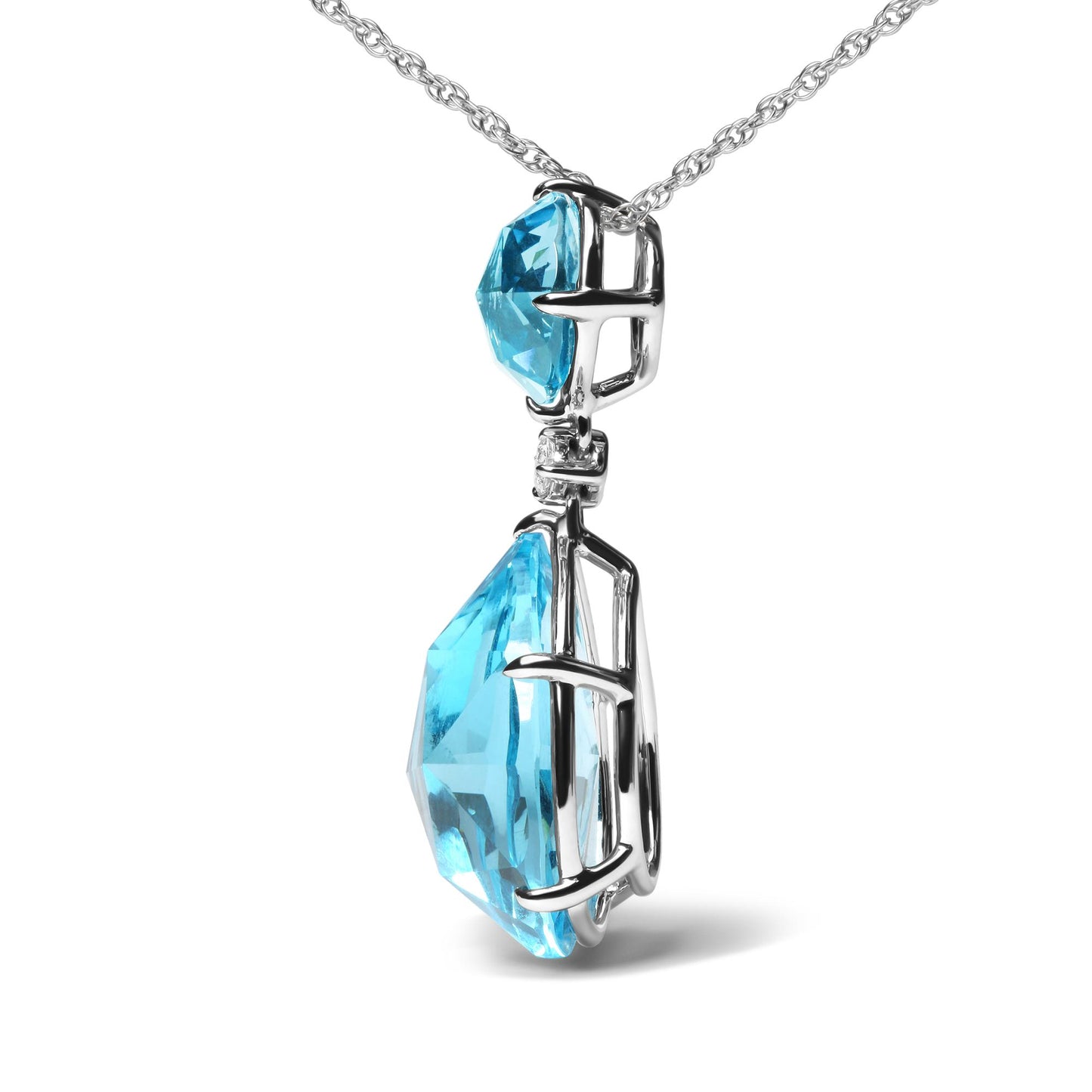 Close-up side view of a white metal necklace pendant featuring a pear-shaped blue gemstone, a round blue gemstone, and a small round white gemstone, all in prong settings.