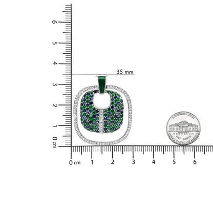 Top-down view of a white metal necklace pendant with an outer border of white round gemstones in prong settings, an inner area filled with blue and green gemstones, shown on a ruler with a coin for size reference.