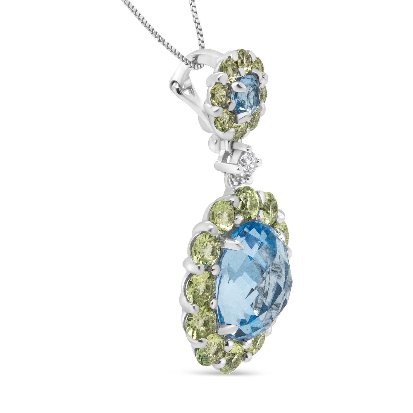 Close-up side view of a white metal necklace pendant featuring one large oval blue gemstone surrounded by multiple small round green gemstones, one small round blue gemstone with surrounding small round green gemstones above it, and a single small round white gemstone connecting the two sections.