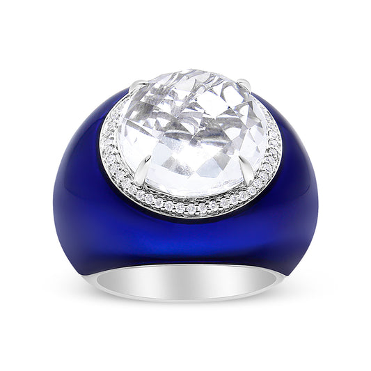 Front angle view of a white metal ring featuring a large round white gemstone in bezel setting, surrounded by small round white gemstones in shared prong setting on a blue band.