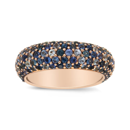 Rose metal band ring with multiple round blue gemstones in prong settings, shown in a close-up side angle.