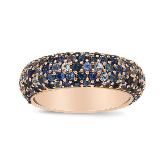 Rose metal band ring with multiple round blue gemstones in prong settings, shown in a close-up side angle.