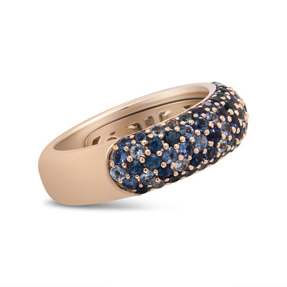 Close-up side angle of a rose-colored ring with multiple round blue gemstones set in prongs on the upper surface.