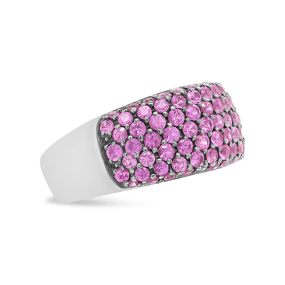 White metal ring with rectangular top surface set with numerous round pink gemstones in prong settings, shown at an angle against a white background.