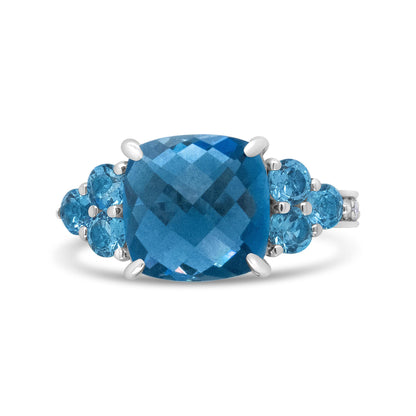Front view of a white metal ring with a large cushion-cut blue gemstone center and smaller round blue gemstones on each side.