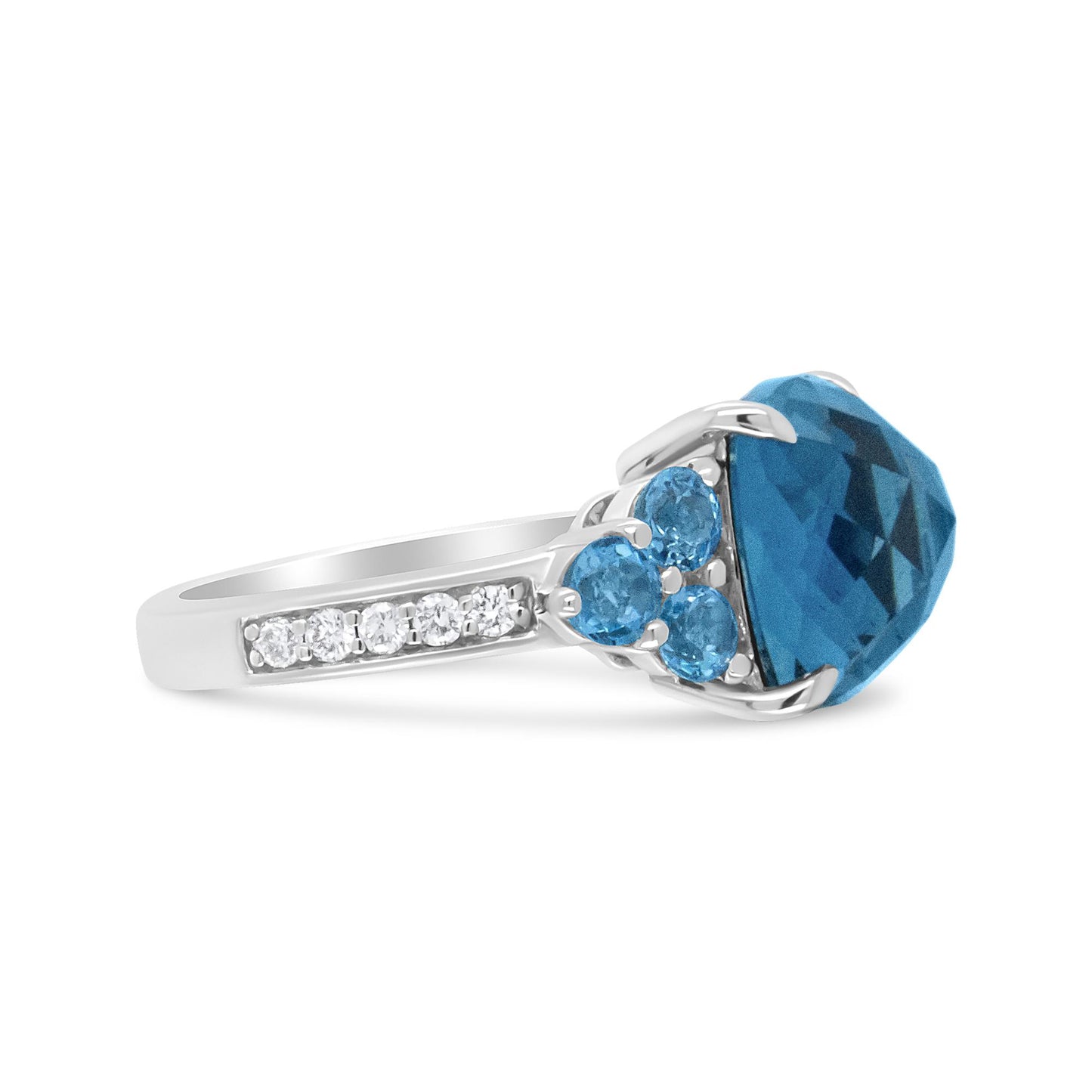 White metal ring with a large blue gemstone center, accented by smaller blue gemstones and a row of white round prong-set gemstones on the band, shown in a side profile angle.