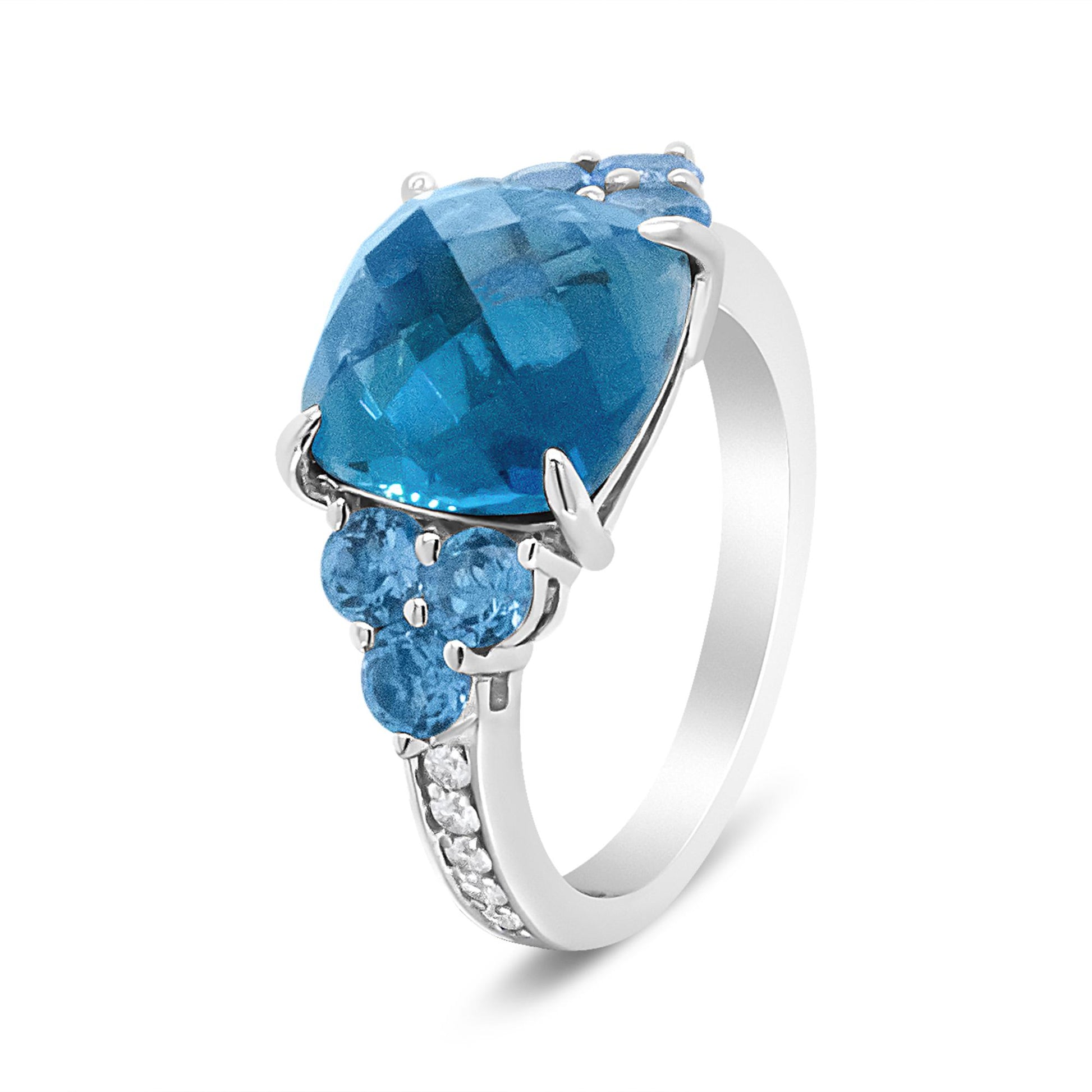 White metal ring with a large blue gemstone centerpiece and smaller blue gemstones on the side, accented by white gemstones along the band, shown at a three-quarter angle.