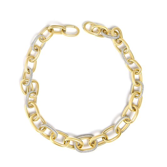 Close-up top view of a yellow metal chain necklace with alternating links, some set with white gemstones in pave setting.
