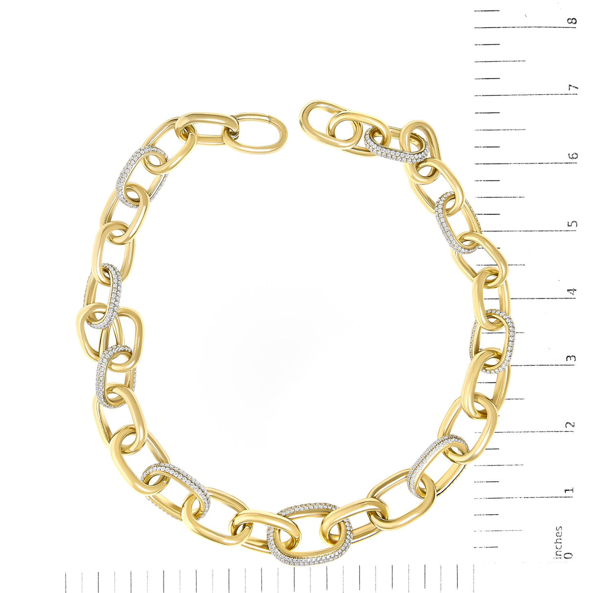 Yellow metal necklace with alternating plain and pave-set white gemstone encrusted oval links, shown on a scale, top-down angle.