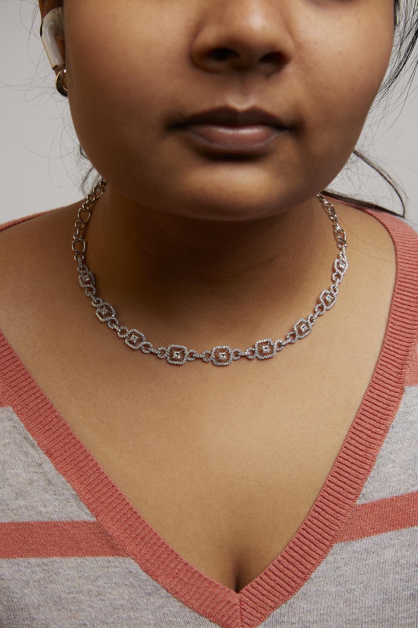 Close-up front view of a model wearing a white metal necklace featuring alternating square and round white gemstones in prong settings.