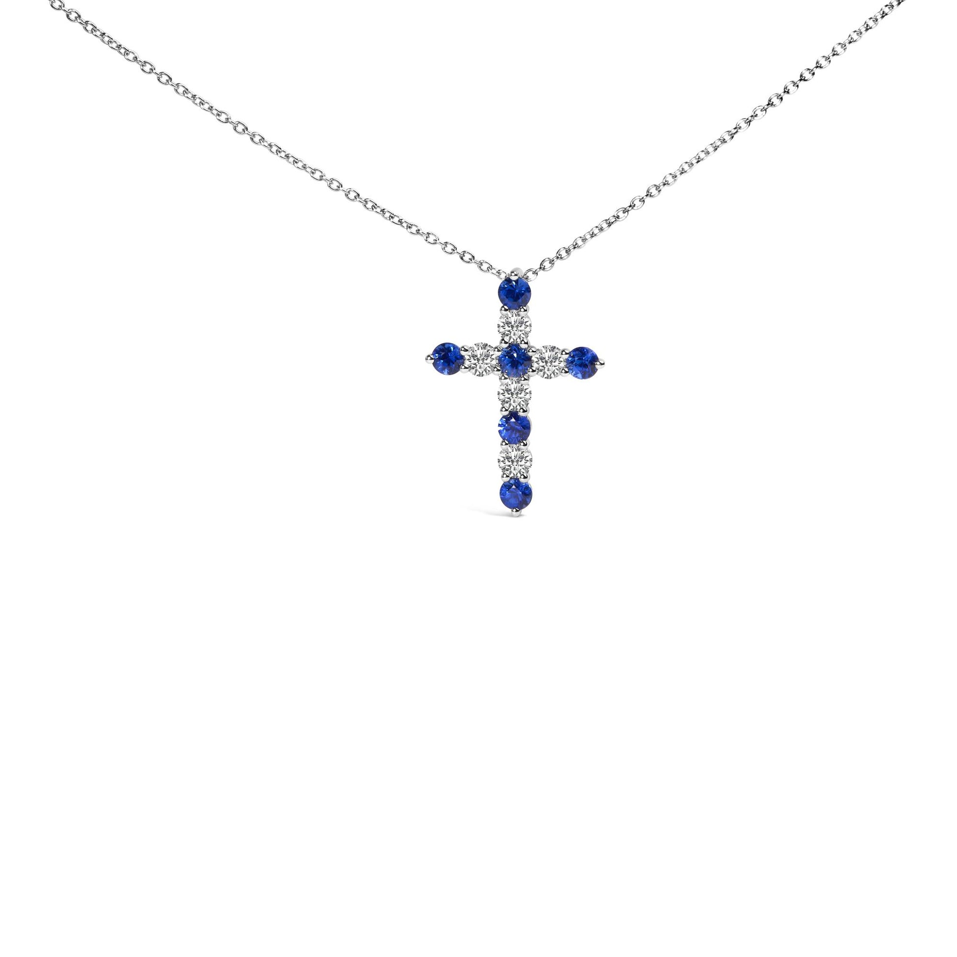 White metal necklace with a cross-shaped pendant featuring round white and blue gemstones in prong settings, shown from a front angle.
