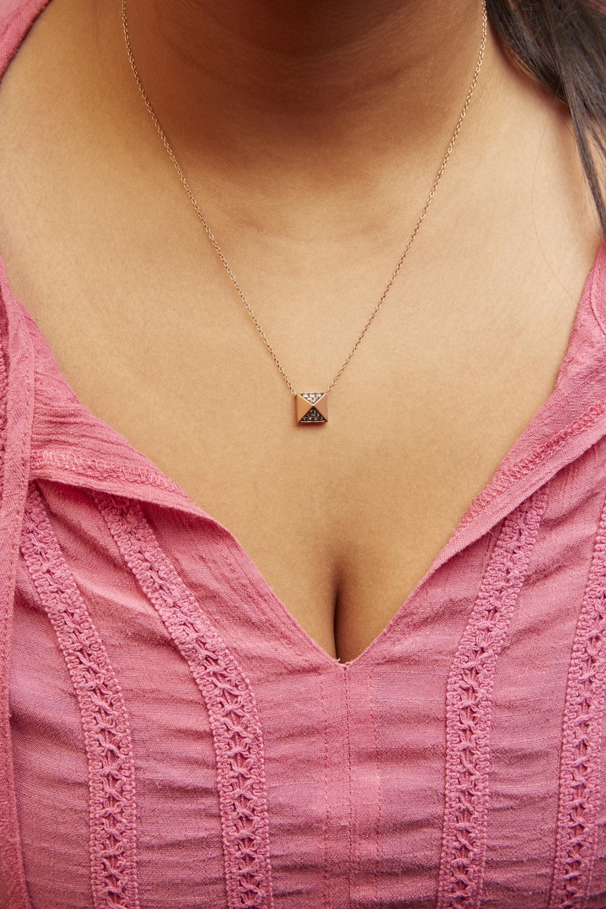 Front view of 14K rose gold pyramid pendant necklace showcasing brown diamond pave on a model in pink clothing
