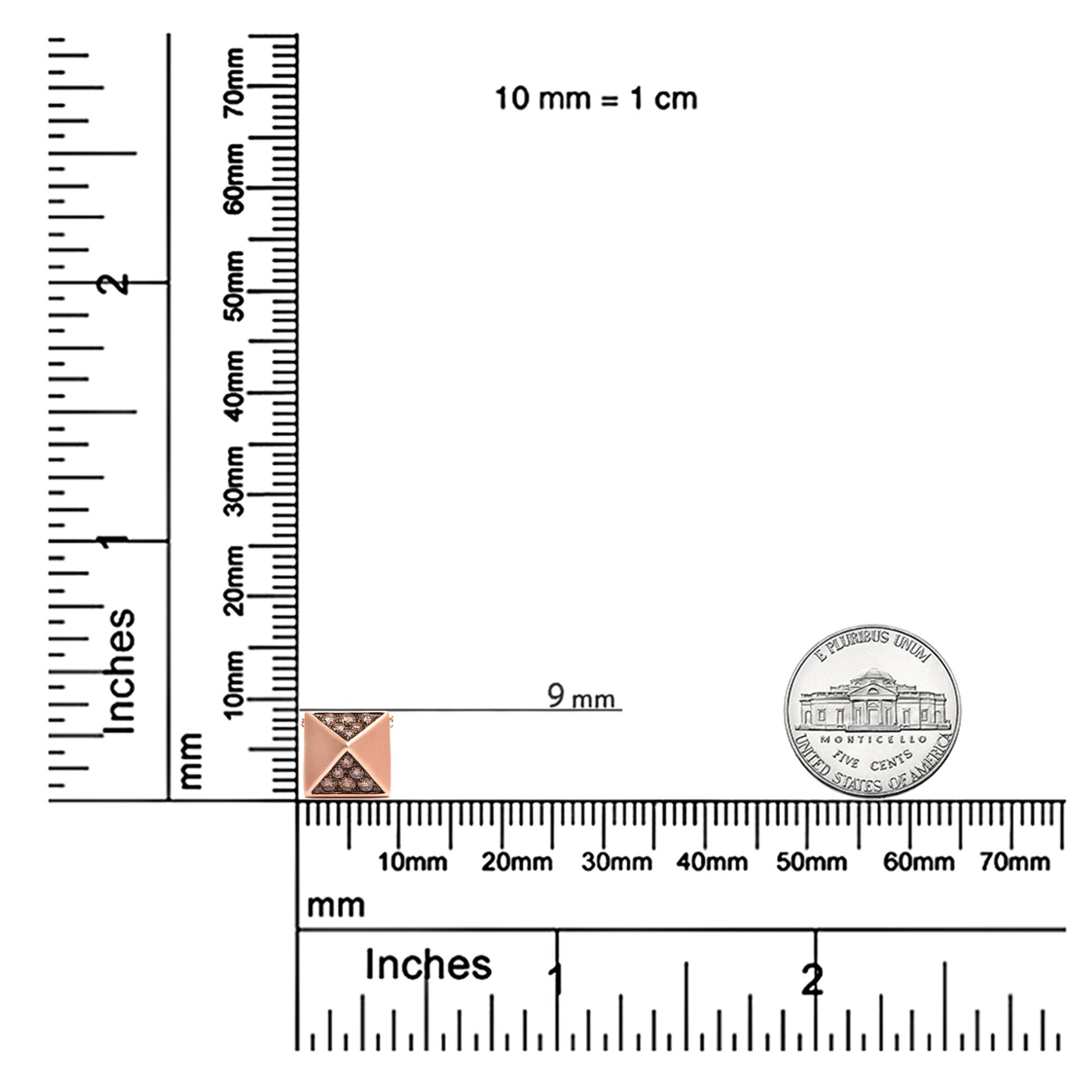 Rose metal necklace pendant with round brown gemstones in pave setting, displayed on a ruler and coin for size reference, front angle.