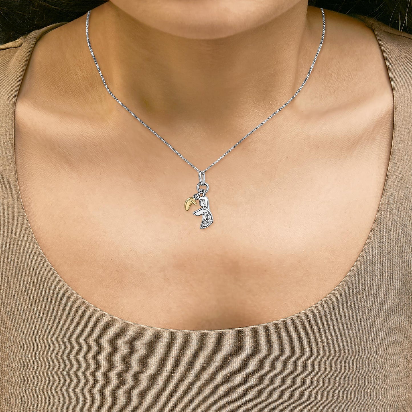 Necklace shown worn on a model featuring a yellow metal crescent charm and a silver-tone charm with white gemstones, shot from the front.