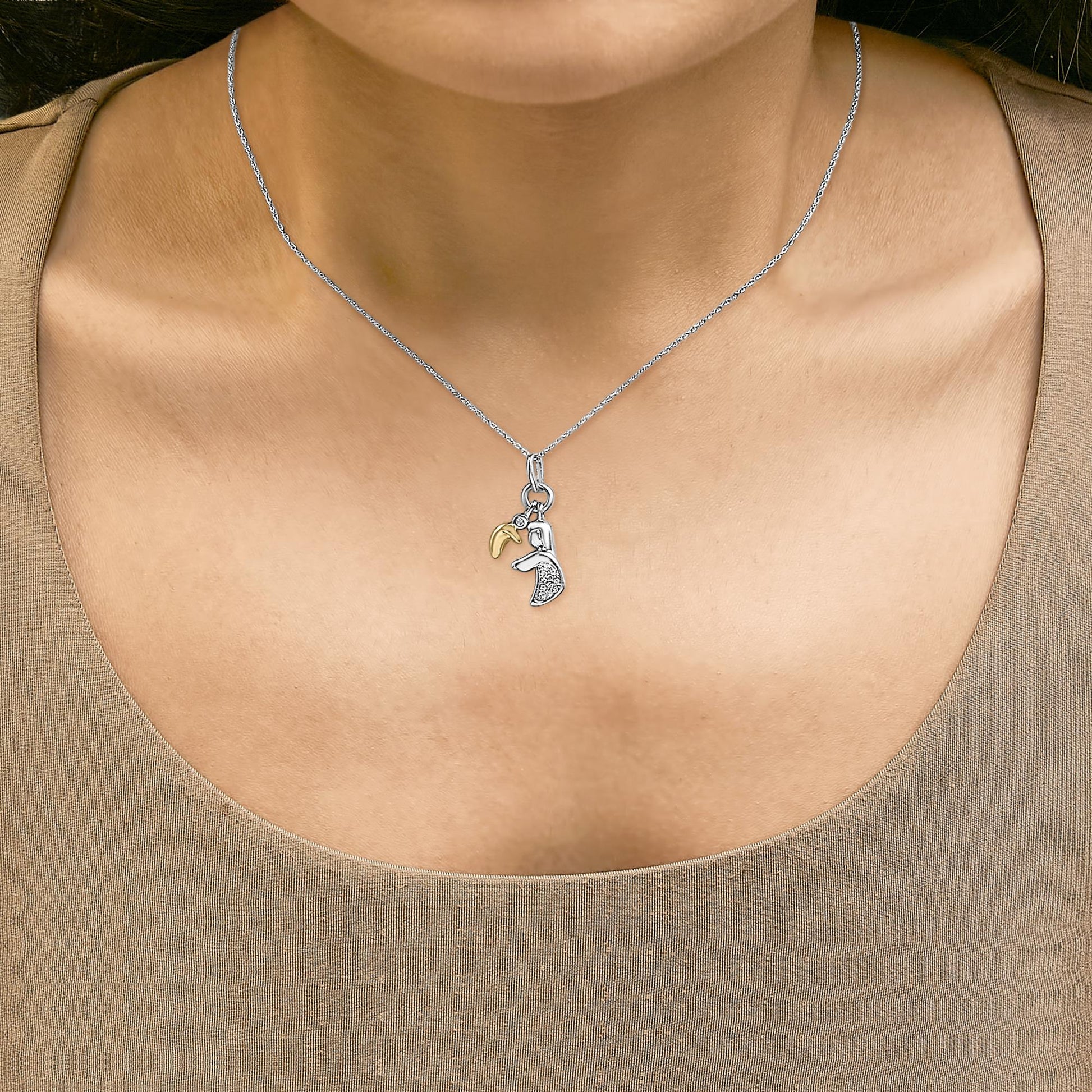 Necklace shown worn on a model featuring a yellow metal crescent charm and a silver-tone charm with white gemstones, shot from the front.