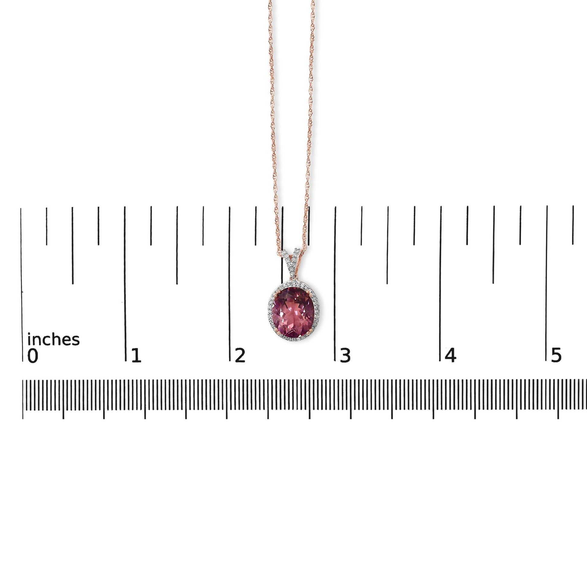 Rose-colored necklace with a pink oval gemstone pendant surrounded by small white gemstones, shown on a scale, front-facing angle.