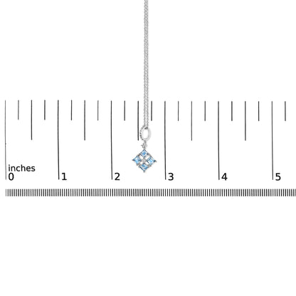 White metal necklace with a pendant of four blue square gemstones arranged in a diamond shape, accented with small white round gemstones, shown hanging against a ruler for scale, front view.
