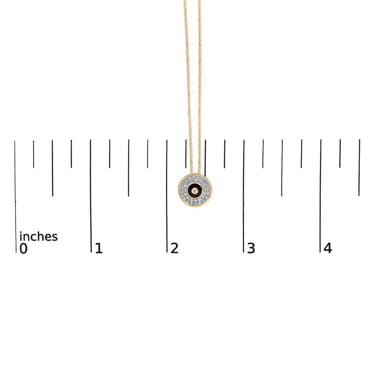 Yellow metal chain necklace with circular pendant featuring one central white gemstone in bezel setting surrounded by multiple white gemstones in prong setting and a black enamel detail, shown hanging on a scale from a front angle.