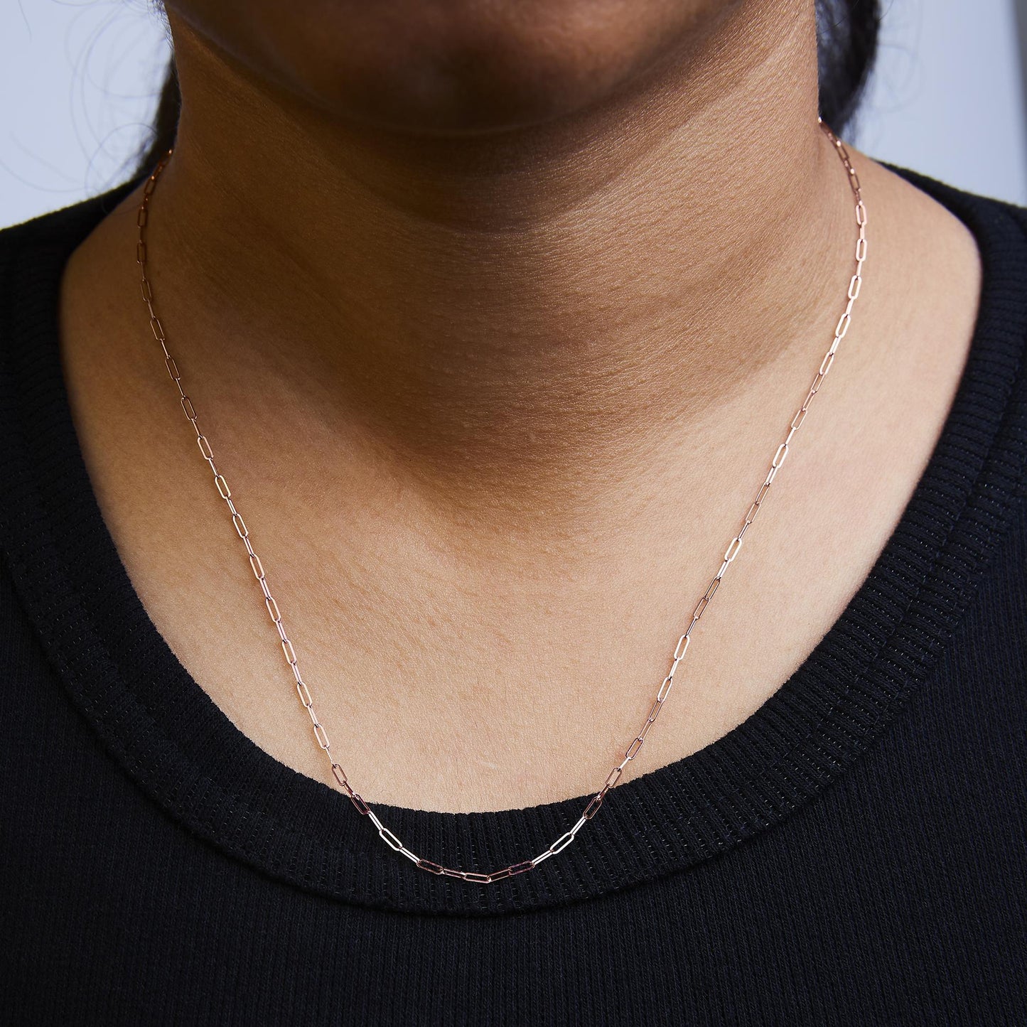 Rose-colored chain with elongated links shown worn on a model, front close-up angle.