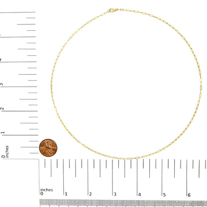 Top-down view of a delicate yellow chain necklace displayed on a ruler and scale for size reference with a penny for scale.