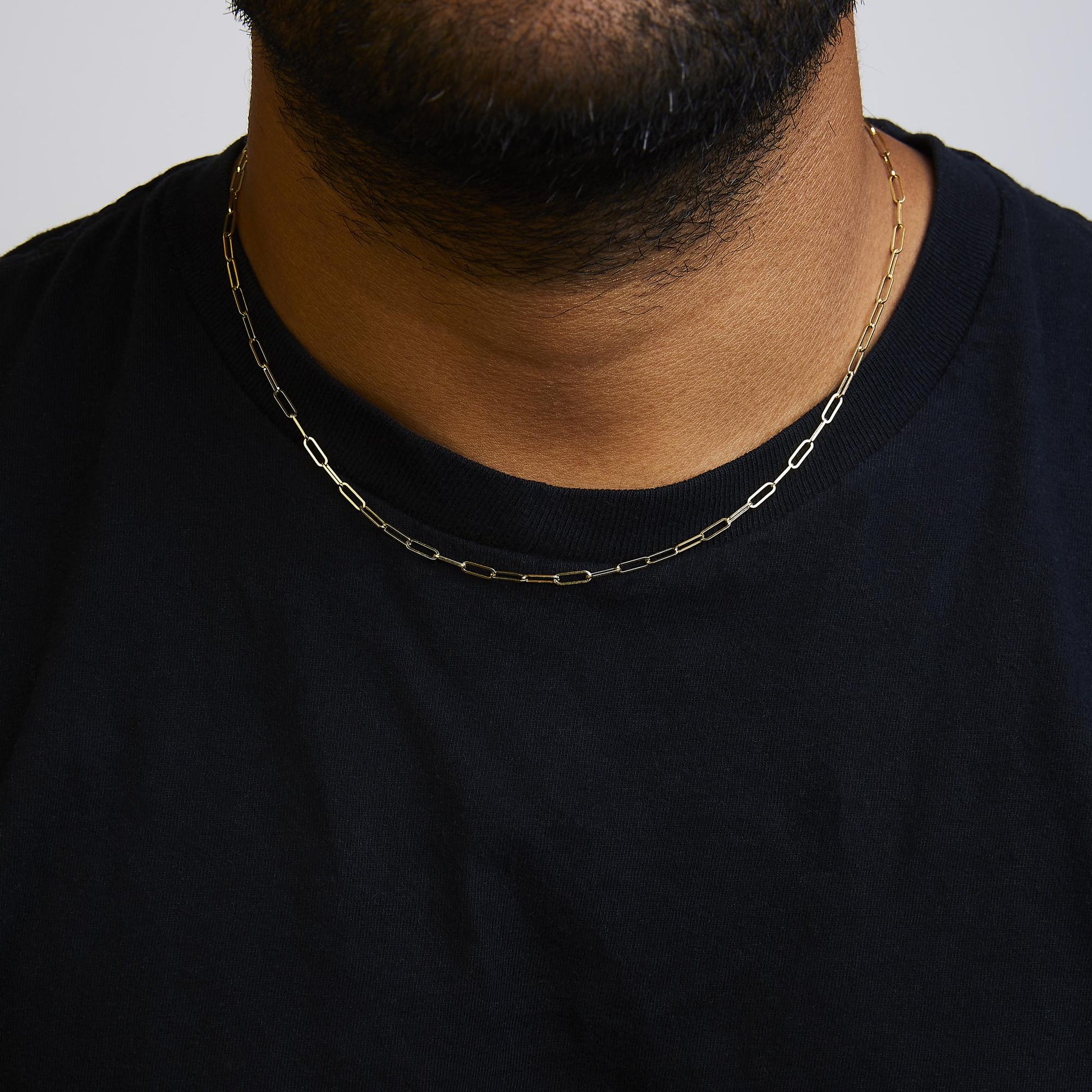 Yellow metal chain with elongated links shown worn on a model’s neck from a front angle.