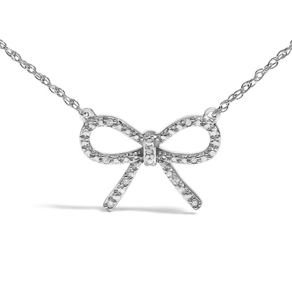 Front view of a white metal bow-shaped necklace pendant adorned with round white gemstones in prong settings, shown on a white background.