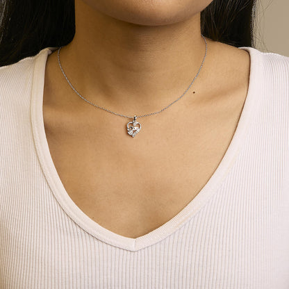 Front view of a white metal necklace with a heart-shaped pendant featuring seven white round gemstones in prong settings, worn on a model.