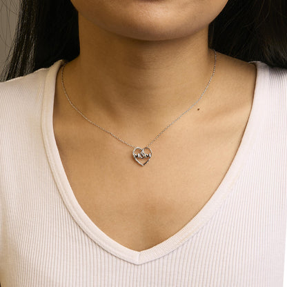 Close-up front view of a white metal necklace with a heart-shaped pendant featuring white round gemstones in prong settings, worn on a model.
