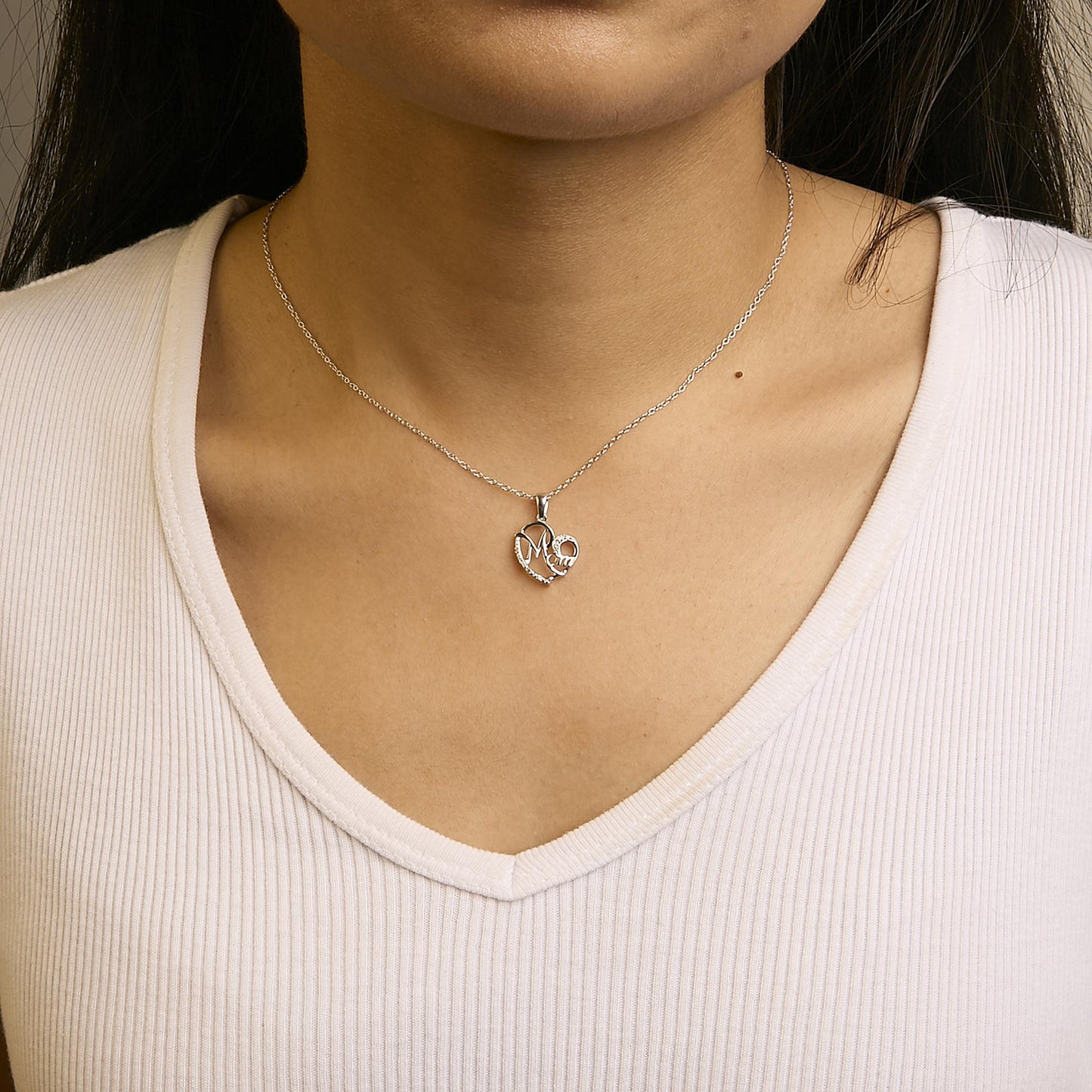 White metal necklace with a heart-shaped pendant featuring round white gemstones in a prong setting, worn on a model, front angle.