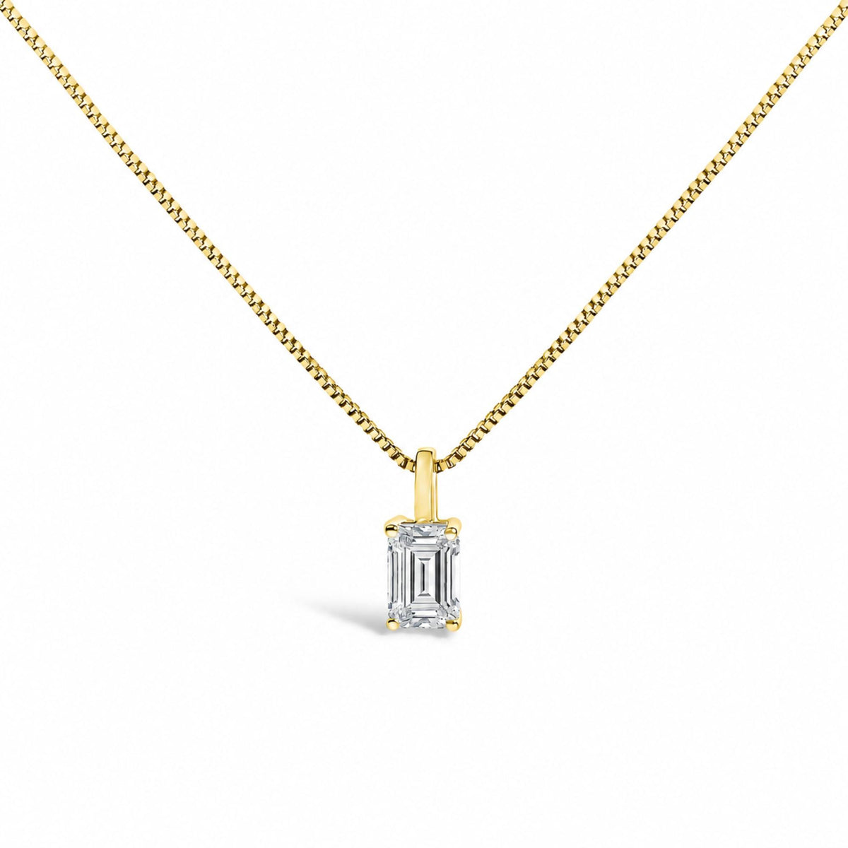Close-up front view of a yellow metal necklace with a pendant featuring a white emerald-shaped gemstone held by a four-prong setting.