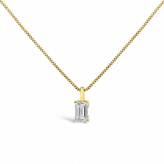 Close-up front view of a yellow metal necklace with a pendant featuring a white emerald-shaped gemstone held by a four-prong setting.