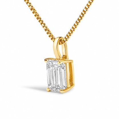 Close-up front angle of a yellow metal necklace with a pendant featuring a single emerald-shaped white gemstone in a four-prong setting.