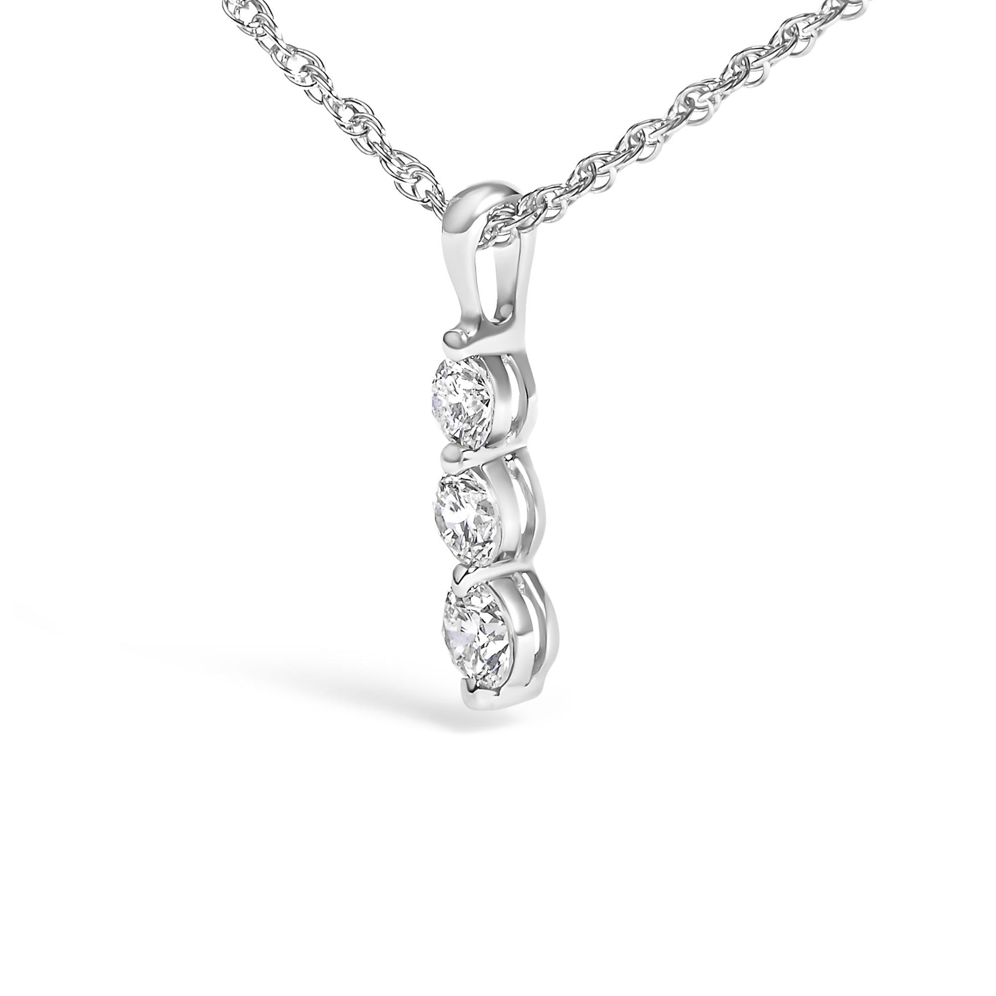 Close-up angled view of a white necklace pendant with three round white gemstones in prong settings suspended from a twisted chain.